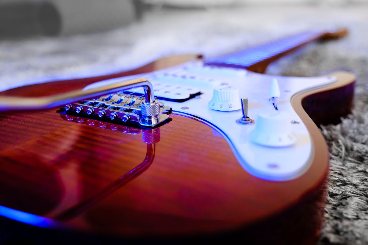 Detailed close-up of an electric guitar with vibrant lighting placed on a plush carpet.