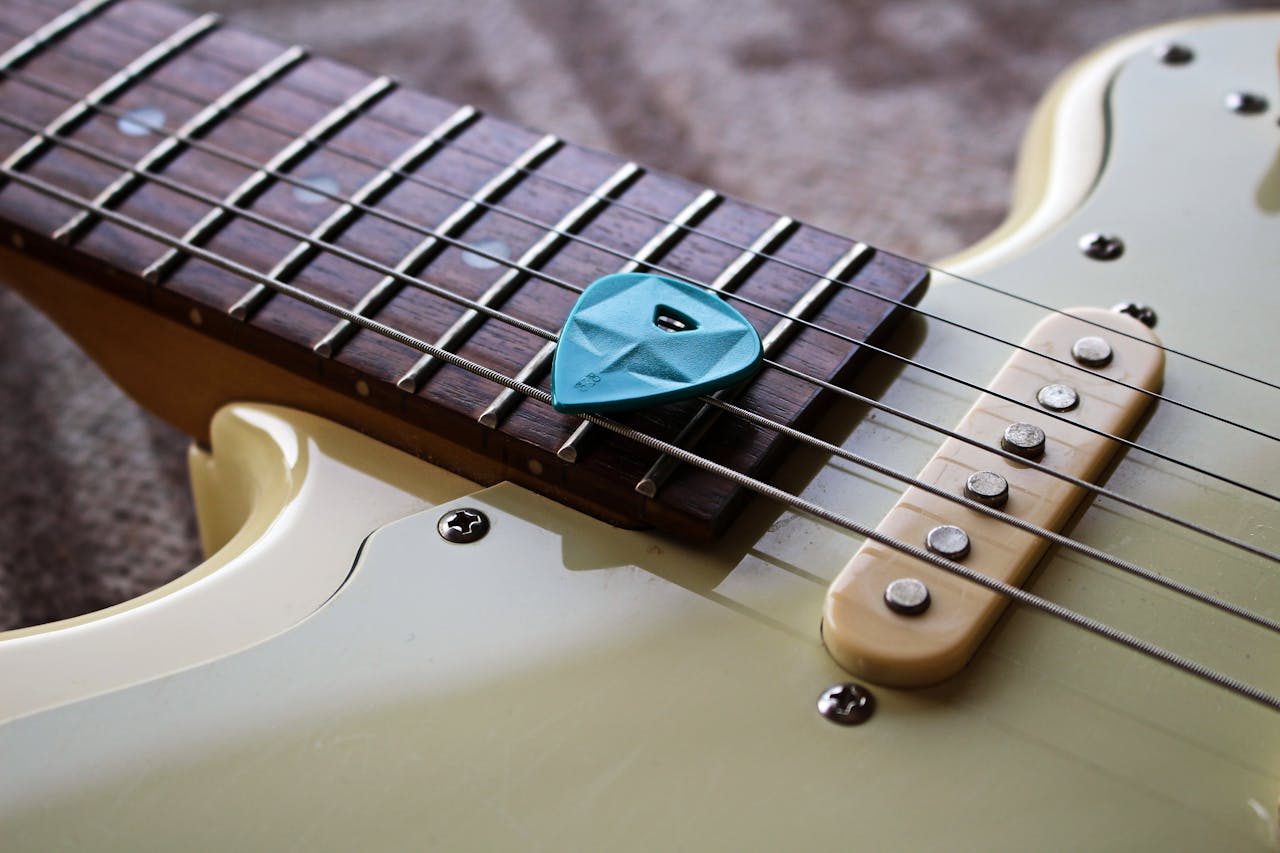 Detailed close-up photo of a guitar neck and strings with a blue pick.
